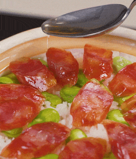 大米出現(xiàn)小孔時開蓋放香腸，往鍋邊淋入少許油，再燜煮8~10分鐘左右。