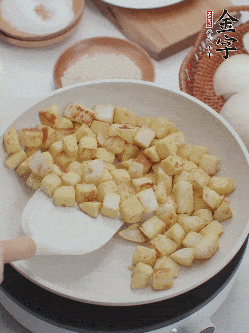 起鍋熱油，倒入饅頭丁，小火煎至蛋液凝固定型再翻面，饅頭丁部煎至金黃時(shí)盛起待用。