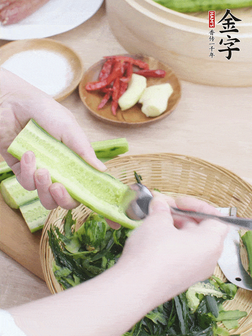 黃瓜削皮，對半切開，勺子挖去內(nèi)瓤，斜刀切片。青蒜斜刀切段。